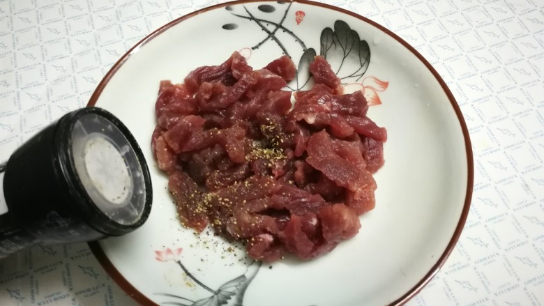 蒜苔炒牛肉,将黑胡椒粒摩擦成黑胡椒碎,放入盘中