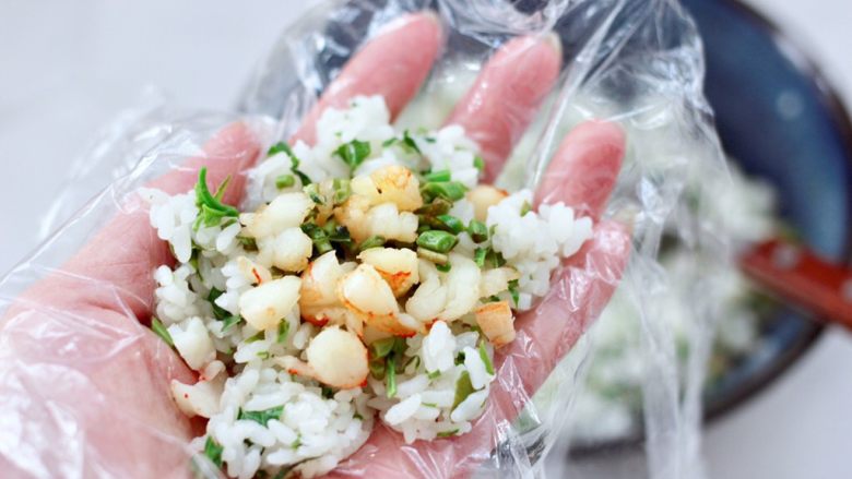 香椿红虾饭团,保鲜膜底下铺一层搅拌好的米饭,中间放入适量炒好的馅料。