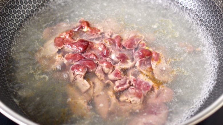 香脆椒爆蒜苔鸡肝,锅中倒入适量,加入1勺盐烧开,把腌制好的鸡肝下锅。