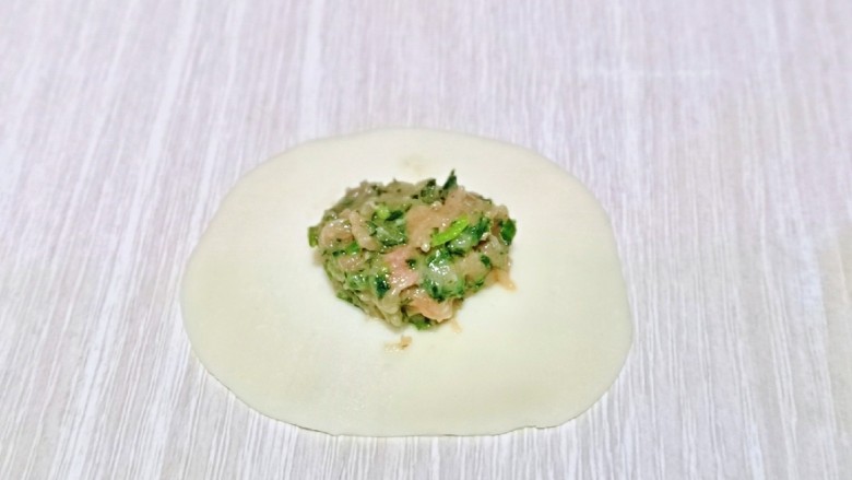 芥菜饺子,取一张<a style='color:red;display:inline-block;' href='/shicai/ 4346'>饺子皮</a>,放上适当的馅。