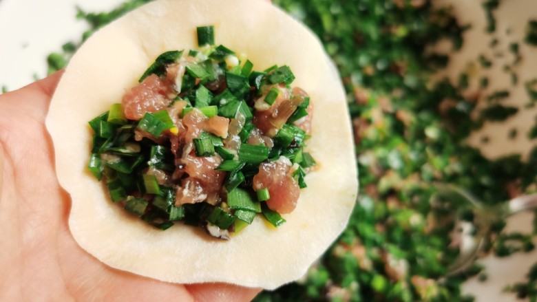 韭菜猪肉馅水饺,将馅料放入饺子皮中间，包成饺子。