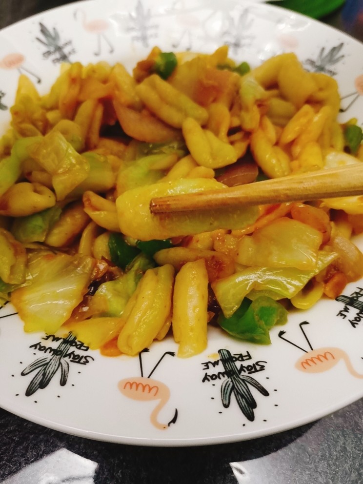 包菜炒猫耳朵,热锅加适量食用油,先把包菜洋葱青椒炒熟,再加入猫耳朵翻炒,调味即可出锅