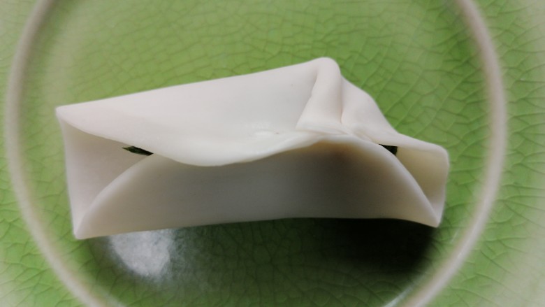 韭菜猪肉馅水饺,将饺子皮对折然后用水粘住中间,然后两边向中间捏褶子
