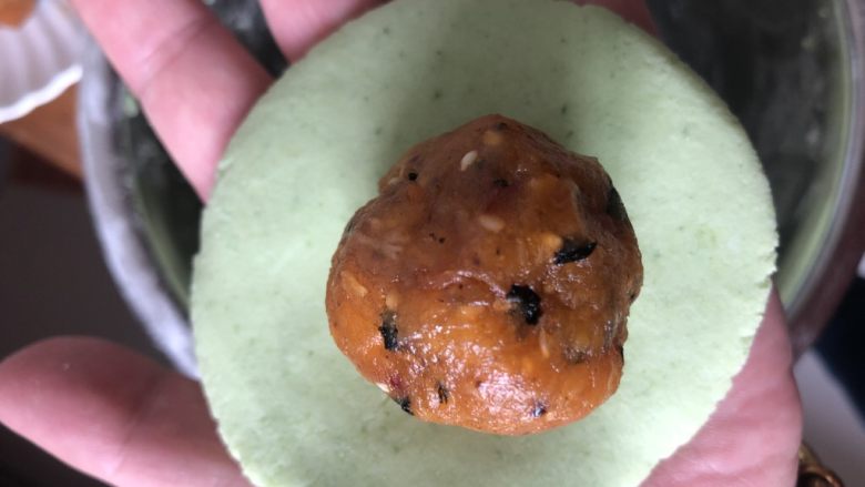蛋黄肉松青团,取一个揉匀后的小面团,大概45g左右,搓圆按扁,中间放一个蛋黄肉松馅。