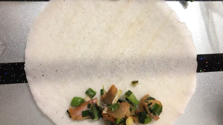 大蒜咸肉春卷,在下边摆上少许大蒜咸肉,如图所示!然后卷起来就可以了。