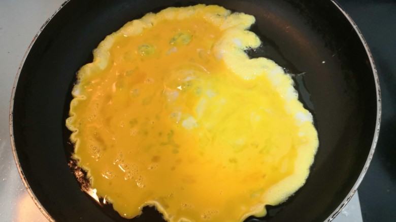 莴笋炒鸡蛋,倒入鸡蛋液,烧至鸡蛋液底部凝固