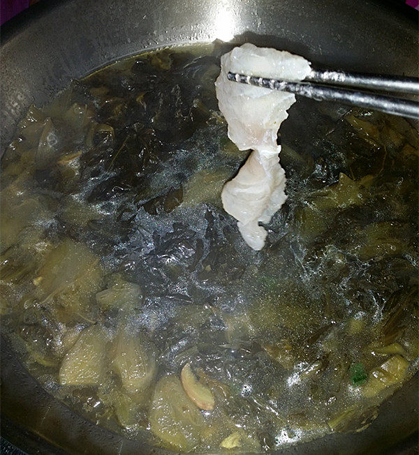 酸汤龙利鱼,将腌好的鱼片一片片,滑入锅中