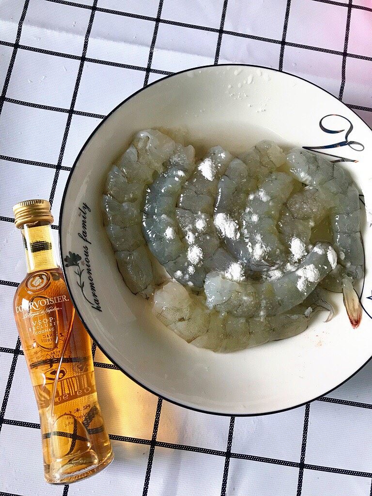 莴笋炒虾仁,家里没料酒,开小瓶的洋酒代替料酒,撒上盐和淀粉,拌匀进行腌制。