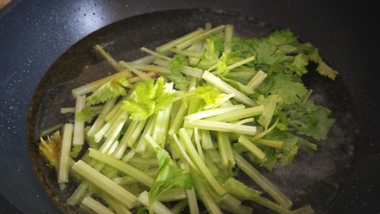 鱿鱼炒芹菜,芹菜倒入锅中。