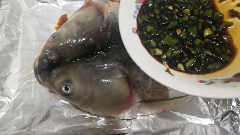 香辣烤鱼头,把青辣椒料汁,铺上鱼头