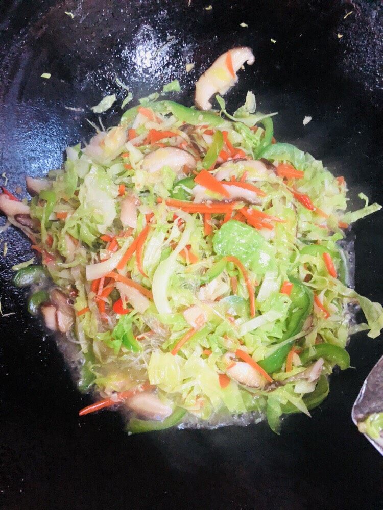 卷心菜炒粉丝,炒匀后加入适量开水继续翻炒,让粉丝再吸收水分。