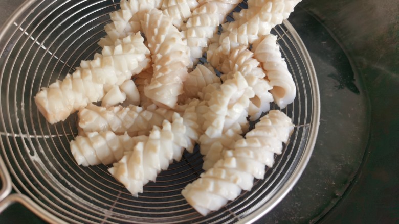 鱿鱼炒芹菜,锅里放水烧开,放入鱿鱼焯水,鱿鱼受热后卷起就变成漂亮的鱿鱼花。