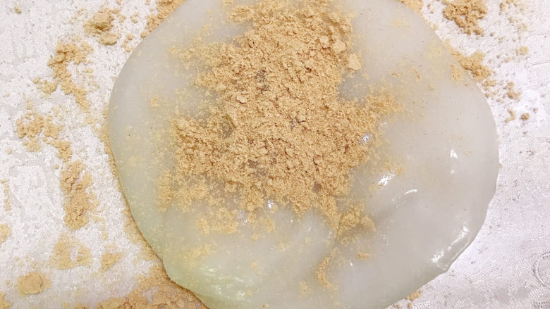 驴打滚,将台面撒上熟黄豆粉,将蒸熟的糯米团放在上面,再撒上一层黄豆粉