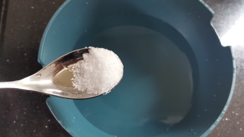 葱油蛏子,取一个盘加入一大勺盐,稍微咸点,加几滴油