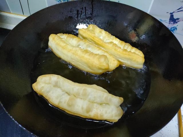 简易香酥大油条&配方&做法分享,锅中烧油到6==7成热是该小火🔥，手抓两端捏紧拉长后放油中炸时慢慢不停的用筷子翻转，是一条受热均匀，上色
