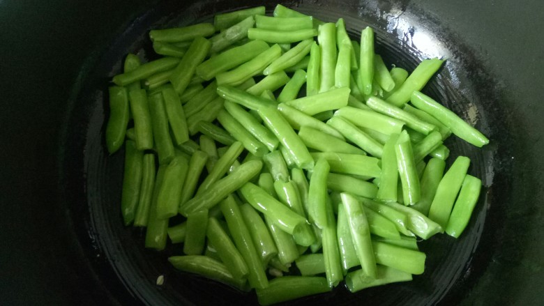 橄榄菜炒四季豆,锅中放入食用油,烧至五层热,加入焯水的四季豆小火煸炒