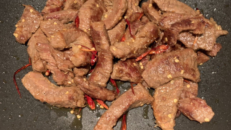 自制牛肉干,炒锅放油,小火煎牛肉条,把水分煎干,爱吃辣可以放些辣子