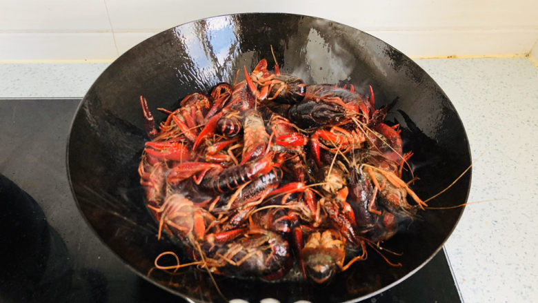 蒜香小龙虾,锅内倒入适量食用油,把小龙虾倒入油锅中过油炸一遍,颜色变红后关火。