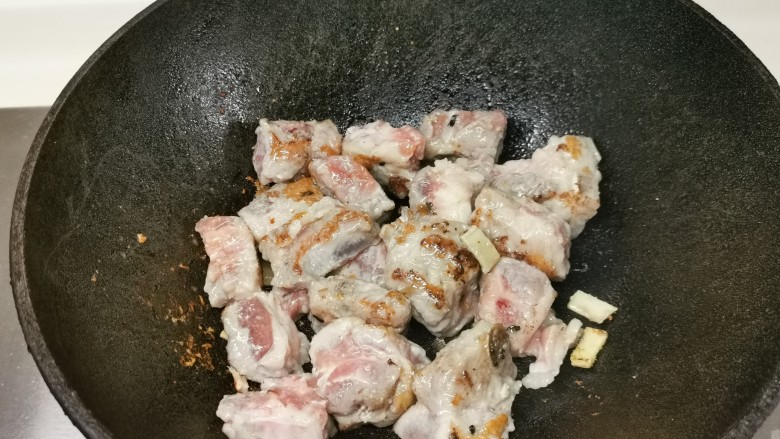四季豆烧排骨,烧热锅下油,放蒜爆香,下排骨,煎两面金黄色。