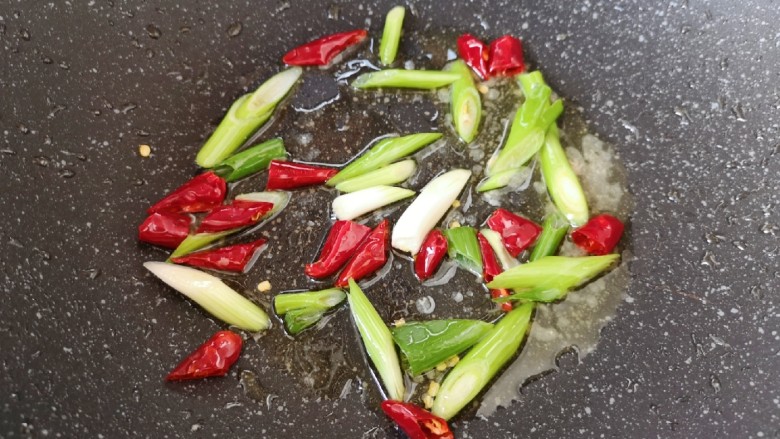 山药炒肉片,锅底留余油,下入小葱和干红辣椒炒香。