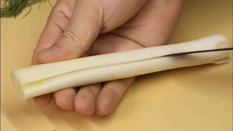 葱油鲈鱼,大葱段先划一刀,再给它延展摊开,然后和葱一样对折卷起来
