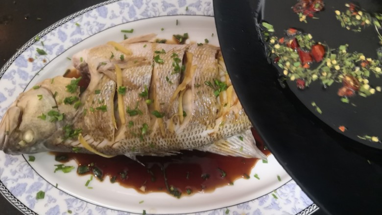葱油鲈鱼,爆香后,淋上鱼生