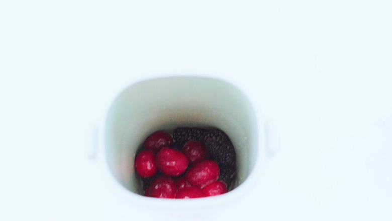 蔓越莓桑葚气泡水,榨汁杯里先放入蔓越莓果和桑葚,加入蜂蜜。