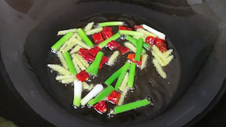 油焖蚕豆,炒锅内倒适量的食用油烧热,下入葱白、姜丝和干红辣椒炒香。