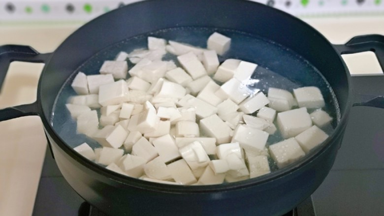 海带豆腐汤,锅中加入水烧开,下豆腐块焯水,大火煮1分钟捞出淋干水分。