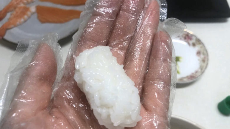 三文鱼寿司,取大小合适的一坨米饭,捏紧称这样的形状