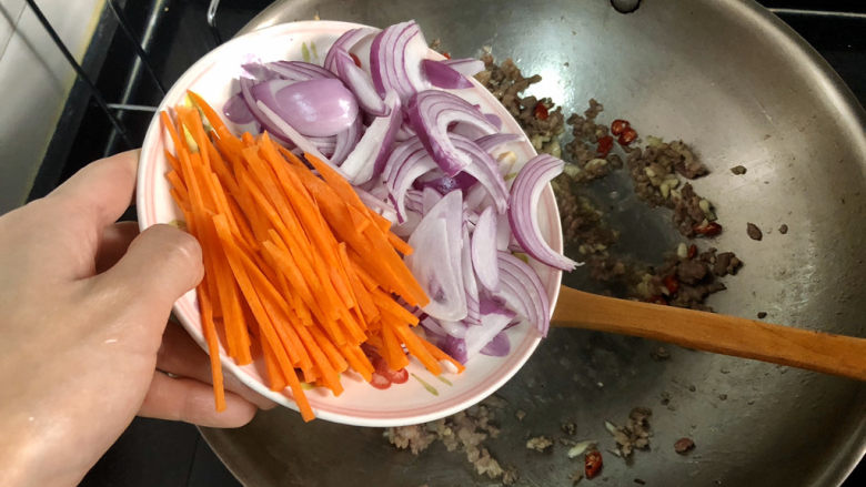 杏鲍菇炒牛肉,转中火,加入胡萝卜丝洋葱,煸炒到洋葱胡萝卜变软