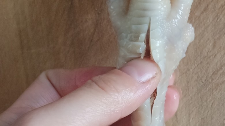 无骨蒜香鸡爪,用刀在鸡爪背部下端划一刀长长的口,用大拇指沿着这个刀口从上至下划一遍,使肉和骨头分离开,如图
