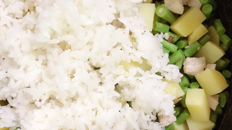 土豆焖饭,倒入电饭锅中,将米饭铺在上面