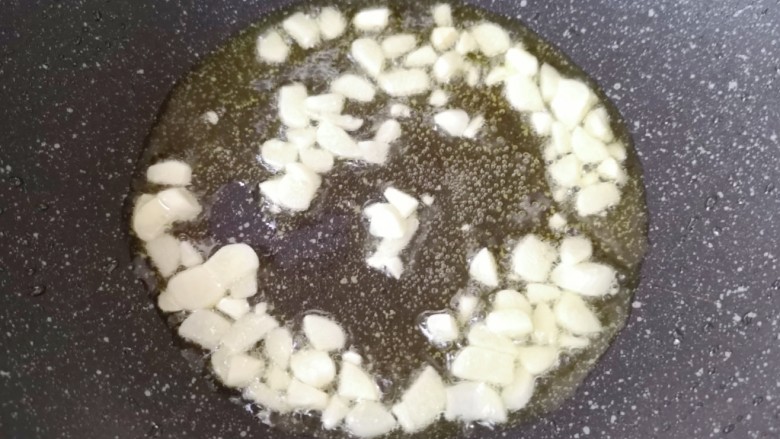 豇豆烧茄子,炒锅内倒适量的食用油烧热,下入大蒜炒香。