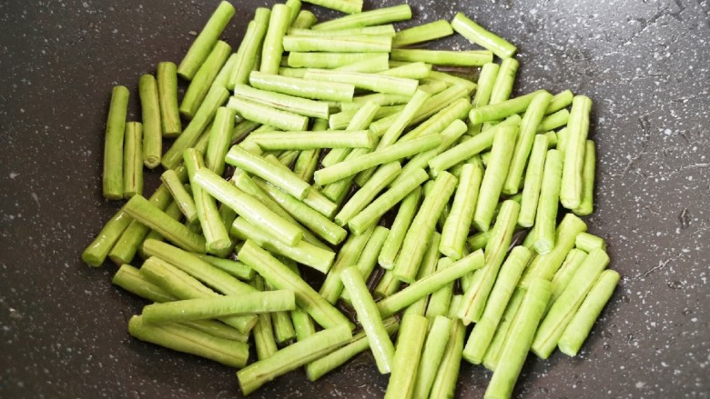 豇豆烧茄子,炒锅内倒多一点食用油烧热，下入豇豆段。