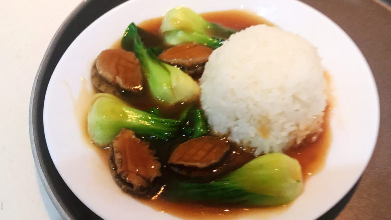 鲍鱼捞饭,用一个小碗把米饭盛出来压实,放入盘中,加入油菜和鲍鱼即可,鲍鱼捞饭做好了~