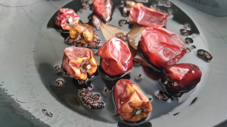 香辣卤鸡爪,锅里放油烧热,下入辣椒,花椒、桂皮等香料炒香。