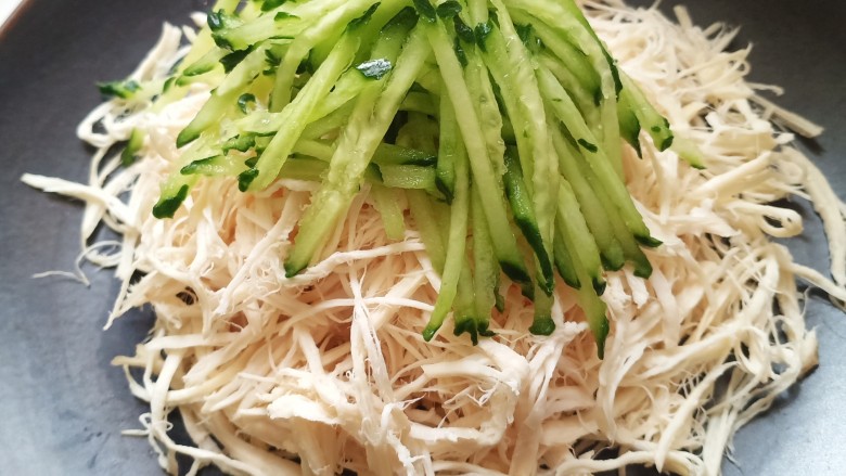 手撕鸡胸肉,把鸡丝放到盘子上码好,最上面放上黄瓜丝