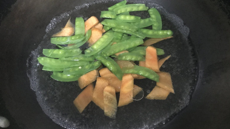 爆炒猪耳朵,炒锅烧沸水,淋少许油和食盐,放入荷兰豆和胡萝卜