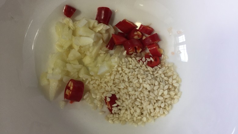 凉拌鸡胗,准备调料碗,碗里放入蒜末和白芝麻,小红椒