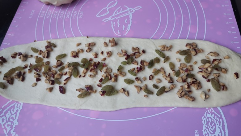 红枣葡萄干吐司,醒发好的面团搓成长条,用擀面杖擀开,散上葡萄干,红枣丁