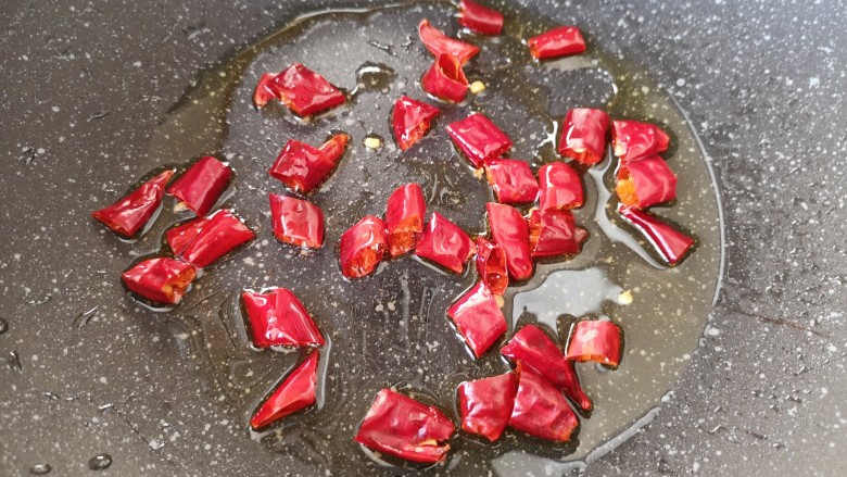 酸豆角炒鸡胗,炒锅内倒适量的食用油烧热,下入干红辣椒中火炒香。