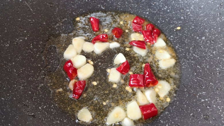 丝瓜炒毛豆,锅底留余油,下入干红辣椒和蒜片炒香。