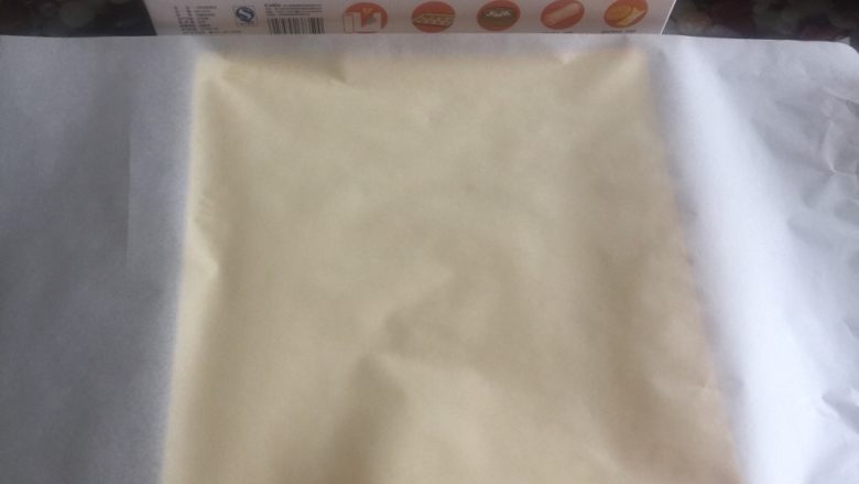 黄桃奶油蛋糕卷,上下均盖上一层油纸,防止蛋糕卷暴露在空气中失去水份。