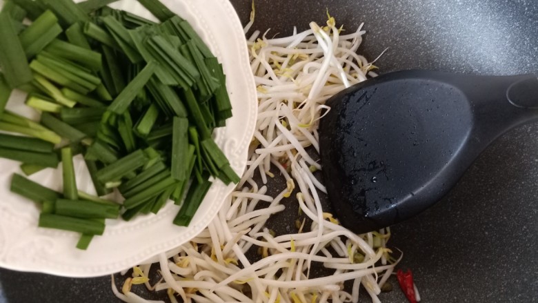 韭菜炒豆芽,再加入韭菜翻炒。韭菜同样翻炒几下,也不要炒过