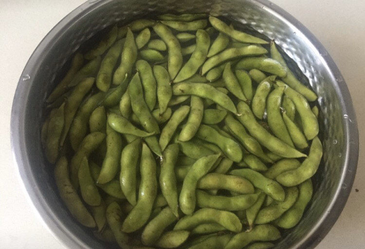 雪菜炒毛豆,毛豆放在清水里浸泡5分钟,水里放一勺食用盐。