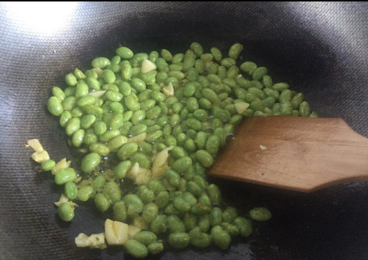 雪菜炒毛豆,另起油锅,放入蒜泥,加入毛豆一起爆炒,加入盐炒至毛豆入味。
