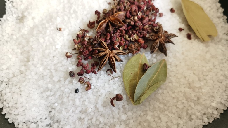 盐焗鹌鹑蛋,将盐放入炒锅,加入花椒八角等香料,小火翻炒。