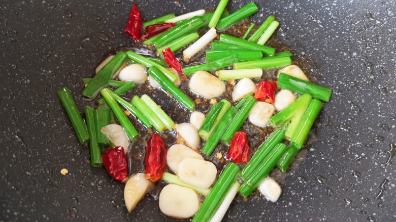 豆芽炒粉条,锅里继续倒入食用油烧热,下入葱、蒜和干红辣椒炒香。