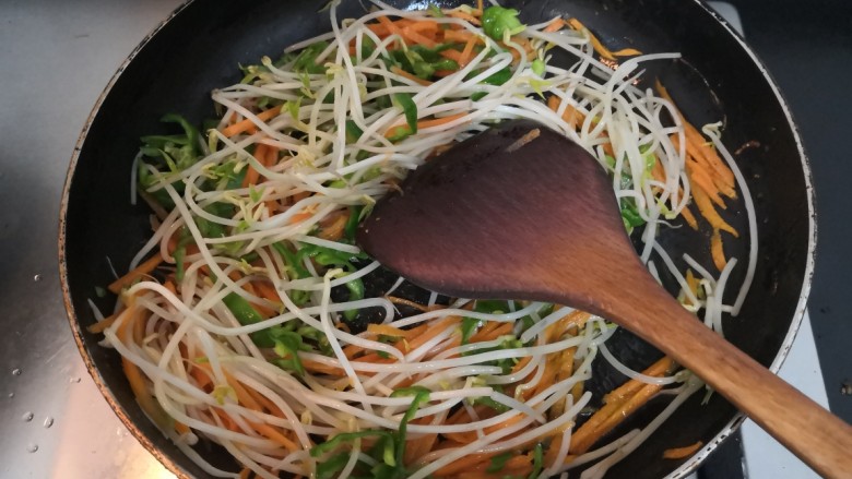 豆芽炒粉条,把胡萝卜,青椒和豆芽,翻炒均匀,至回软断生